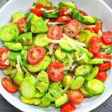 Fresh cucumber, cherry tomato, red onion, and avocado salad in a white bowl, garnished with herbs, showcasing vibrant colors and healthy ingredients, perfect for a nutritious meal.
